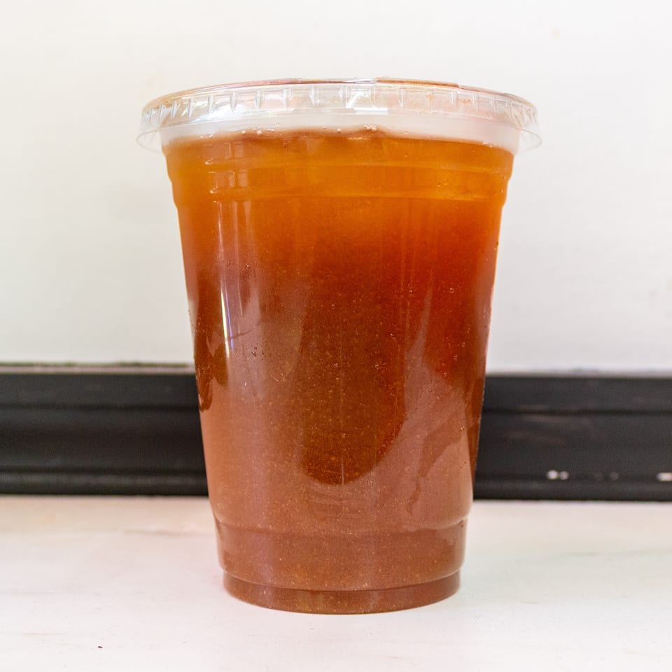 Clear plastic container filled with thick orange-brown sauce on a white surface.